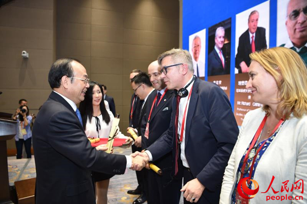 人民日报社社长杨振武为今天成立的人民日报社国际问题研究中心外国专家委员会首批委员颁发聘书。刘龙摄